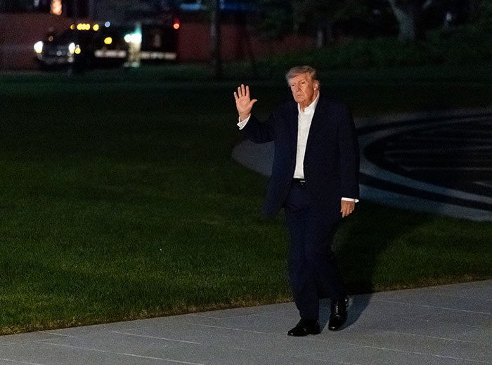 Donald Trump waving as he takes a walk on the White House lawn.
