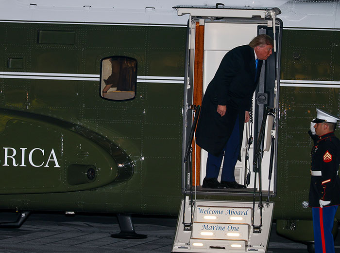 Donald Trump boarding Marine One helicopter at night.