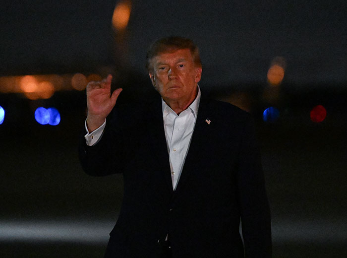 Donald Trump waving under a dark sky, highlighting discussions around Trump's Path To Air Force One.
