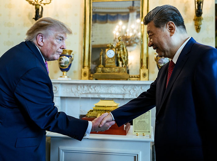 Donald Trump shaking hands with Xi Jinping in a formal room.