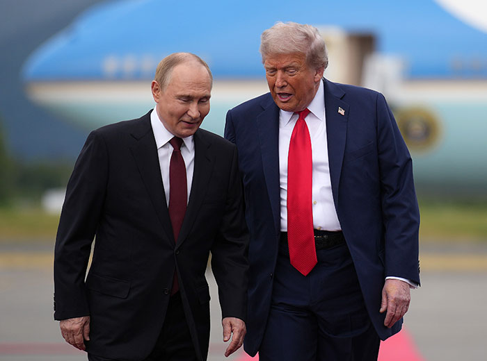 Donald Trump walks with Vladimir Putin near Air Force One, discussing something intently on the runway.